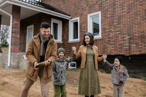 family of four, dressed in brown, gray, and green tones, smiling candidly