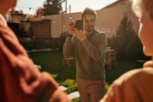 man taking pictures of a family in the backyard