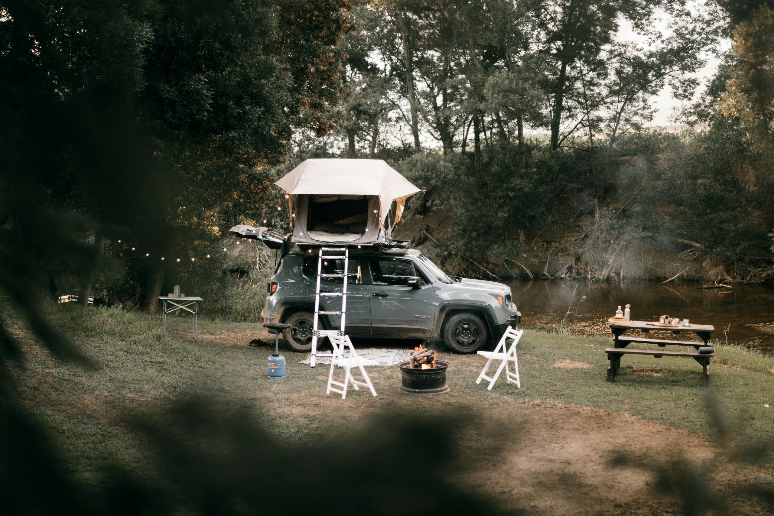 car with a rooftop tent, next to a picnic bench